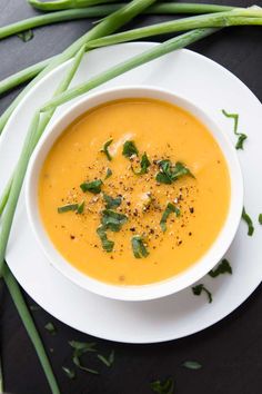 a white bowl filled with soup and garnished with green onions on a black surface