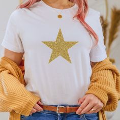 "Soft Cotton T-Shirt with  Glitter Star.  Available in White, Black or Grey. Unisex fashion fit with crew neck and sleeves that can be turned up. Made from 100% Supersoft Organic Cotton (Grey marl 60% cotton, 40% polyester).  Peta approved vegan Ethically sourced Size XS (34\"), S (36\"), M (38\"), L (41\"), XL (43\"),  2XL (47\"), 3XL (51\"), 4XL (56\"), 5XL (61\").  These T shirts are a relaxed fit   Garment Care Instructions: Machine wash on a 30 degree cycle, iron inside out, do not iron over the text or image. Do not tumble dry." Gold Glitter Stars, Star T Shirt, Glitter Stars, Fashion Fits, Star Designs, Unisex Fashion, Stylish Women, Womens Clothing Tops, Black Cotton