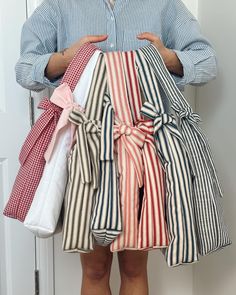 a man is holding several folded shirts in front of his face while standing next to a door