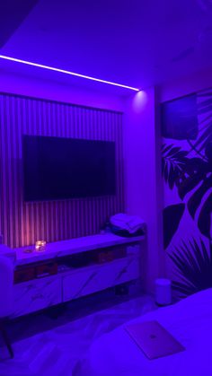 a bedroom with purple lighting and a flat screen tv mounted on the wall above it