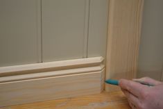 a person is using a pen to paint the trim on a door frame with wood