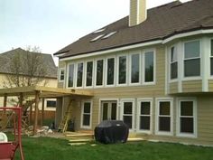 a house being built with windows and sidings on the roof, next to a red wagon in front of it