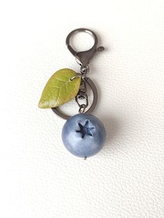 a keychain with a leaf on it and a blue bead attached to it