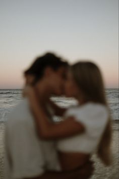 a man and woman kissing on the beach