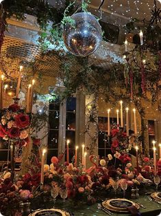 a disco ball hanging from the ceiling above a table with flowers and candles on it