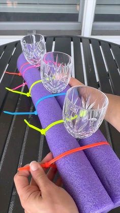 a person is holding some purple paper and plastic cups on top of each other with neon colored bands around them