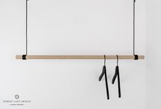 two black handles hang from a wooden bar on a white wall with no one is in it