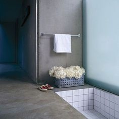 a bathroom with blue walls and white tiles on the floor, along with flowers in a basket