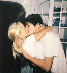 a man and woman kissing each other in the kitchen