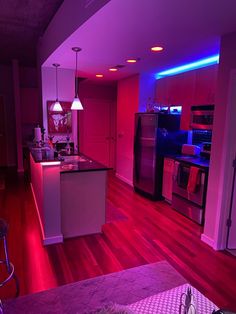 the kitchen is lit up with purple lights and red lighting on the walls, along with stainless steel appliances