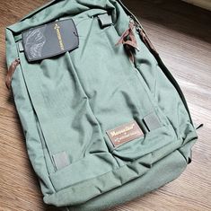 a green backpack sitting on top of a wooden floor