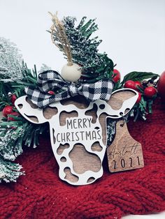 a cow ornament with a merry christmas tag hanging from it's side