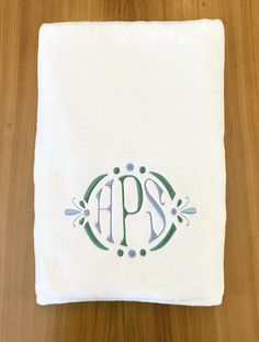 an embroidered monogrammed dish towel on top of a wooden table