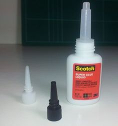 a bottle of glue sitting on top of a table next to a small black marker