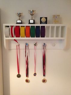 a wall mounted shelf with medals and ribbons on it