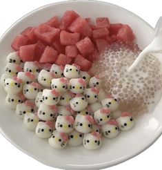 a white plate topped with lots of cut up watermelon and hello kitty candies