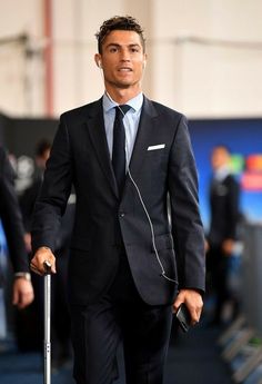 a man in a suit and tie with headphones on walking down the street while holding a cane