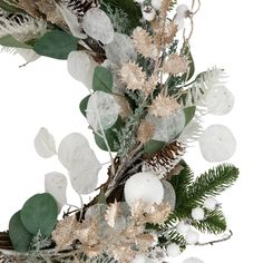 a christmas wreath with white and gold decorations on top of snow covered evergreen leaves, pine cones and other greenery