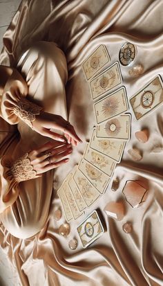 a woman laying on top of a bed with lots of cards and rings around her