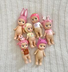 a group of small dolls sitting next to each other on a white cloth covered surface