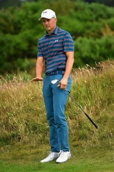 a man standing on top of a lush green field holding a golf ball and club