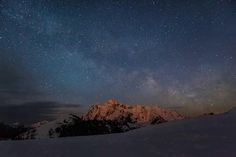 the night sky is filled with stars above snow covered mountains