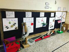 a bulletin board in a school hallway with toys and papers on the wall behind it