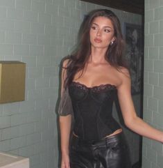 a woman in a black corset standing next to a mirror with her hands on her hips