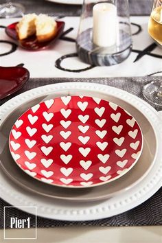 a red and white plate with hearts on it sitting on a table next to wine glasses