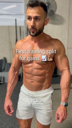 a man with no shirt standing in front of a gym machine and looking at the camera