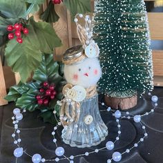 a glass angel ornament next to a christmas tree