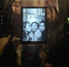 three women are kissing in front of a mirror with the words art house on it