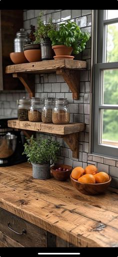 the kitchen counter is made out of wood and has shelves with plants on them, bowls of oranges in front of a window