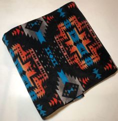 a black and blue blanket with an orange, red, and blue design on it