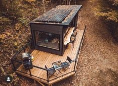 a small cabin in the woods with a table and chairs on it's deck