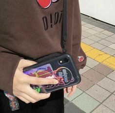 a person holding a cell phone in their hand and wearing a mickey mouse shirt on