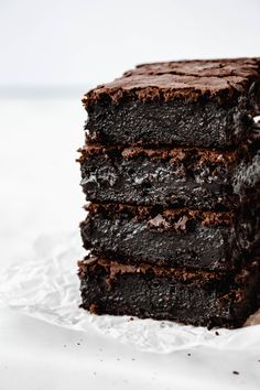 a stack of chocolate brownies sitting on top of a piece of paper covered in frosting