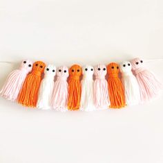 five orange and white tassels with eyes on them