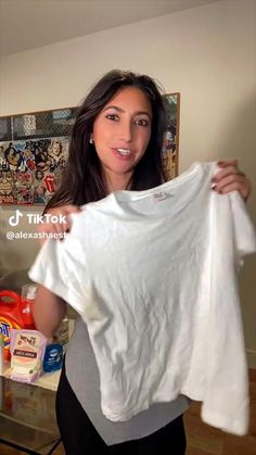 a woman holding up a white t - shirt in her hands