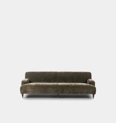 a green couch sitting on top of a white floor next to a gray wall and wooden legs