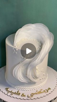 there is a white wedding cake with gold lettering on it and an image of the bride's dress blowing in the wind