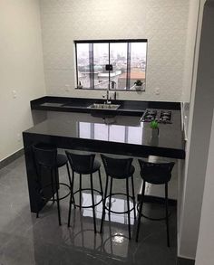 an empty kitchen with black counter tops and stools