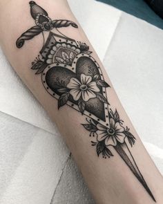 a black and white tattoo on the arm of a person with a knife in it