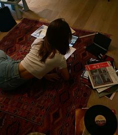 a woman is sitting on the floor with her laptop and papers in front of her