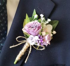 a boutonniere with purple flowers and greenery