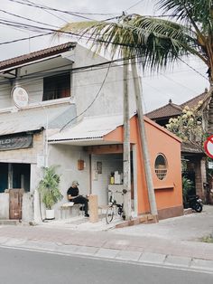 an orange and white building sitting on the side of a road next to a palm tree