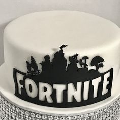 a white cake with the words fortnite in black on it and some silver sparkles