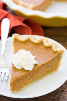 a slice of pumpkin pie on a white plate with a fork and red napkin in the background