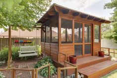 a small wooden house with a white bench on the front porch and side steps leading up to it