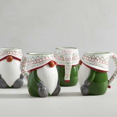 four green and white ceramic mugs with santa's hats on them, sitting next to each other